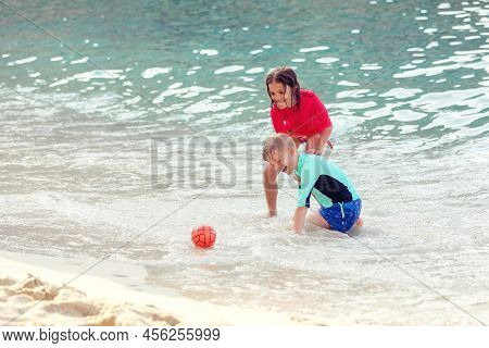 Boy And Girl Playing In Water During Summer Vacation On Ocean Beach