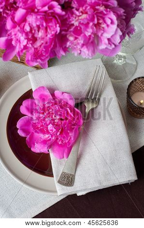 Configuração de tabela com peônias rosa, talheres Vintage e toalha de mesa marrom