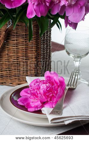 Configuração de tabela com peônias rosa, talheres Vintage e toalha de mesa marrom