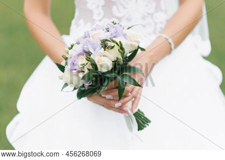 The Bride's Wedding Bouquet Of Milk Roses And Lilac Eustoms In The Hands Of The Bride