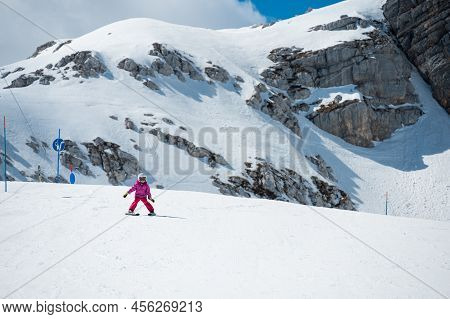 Cute Young Girl Learning To Skii At Winter Resort On A Sunny Day.