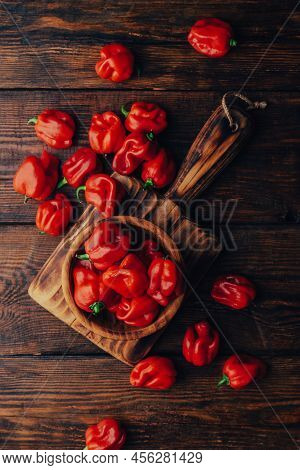 Bowl Full Of Red Habanero Chili Peppers On A Dark Wooden Backdrop. View From Above