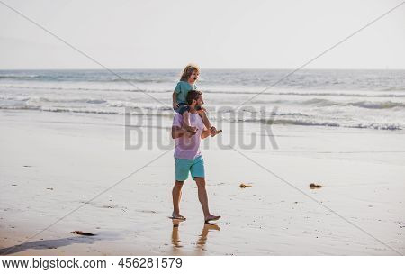 Dad And Child Having Fun Outdoors. Little Boy Kid With Daddy Carrying Him On Shoulders. Father Givin