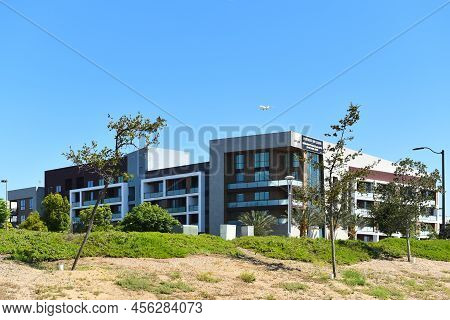 TUSTIN, CALIFORNIA - 12 JUN 2022: Apartments on Redhill Avenue with jet airplane on final approach to John Wayne Airport.