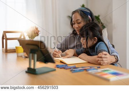 Smiling Senior Grandma And Cute Little Kid Granddaughter Watching Cartoons On Laptop Together, Happy