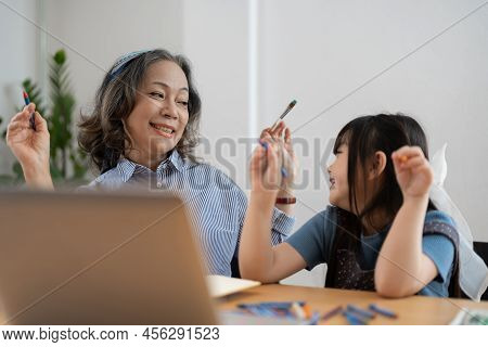 Happy Senior Grandma And Cute Little Kid Granddaughter Watching Cartoons On Laptop Together, Happy O