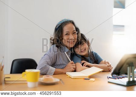 Smiling Senior Grandma And Cute Little Kid Granddaughter Watching Cartoons On Laptop Together, Happy