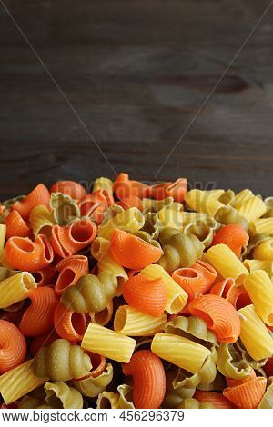Pile Of Various Shapes Three-color Uncooked Vegeroni Pasta On Black Wooden Background