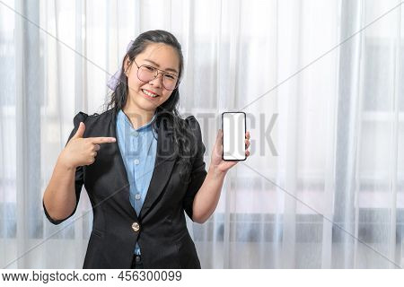 Happy Asian  Woman Fingering Up And Pointing With Mobile Phone White Screen With Her Hand At Copy Sp