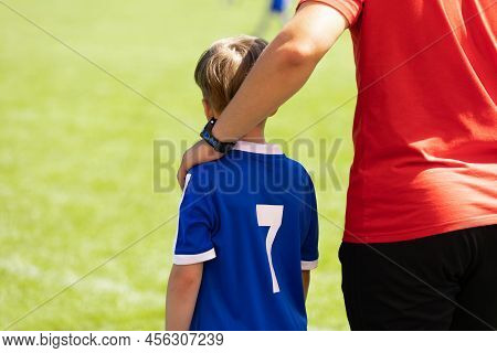 Soccer Coach Holding Hand On Kids Arm. Coach Supprting Young Football Boy. Sporty Boy Ready To Play 
