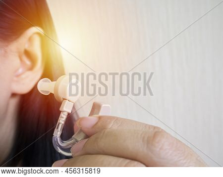 Close-up Of A Woman Hands Putting Hearing Aid In Ear. Close-up Of Doctor Inserting Hearing Aid In Th