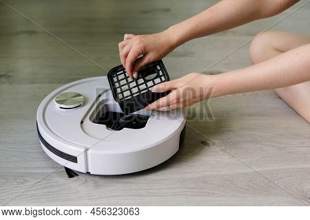Young Woman Taking Out Container And Filter Of Automatic Robot Vacuum Cleaner To Clean It From Dirt 