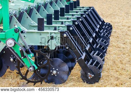 Black Metal Figured Cutters And Harrows Of A Multi-row Cultivator Against The Background Of Stubble 