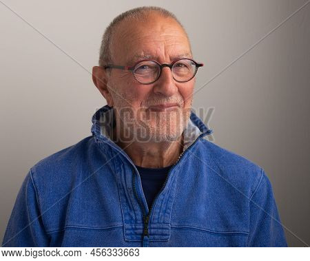 Smiling Older Man Wearing Glasses On A Plain Grey Background