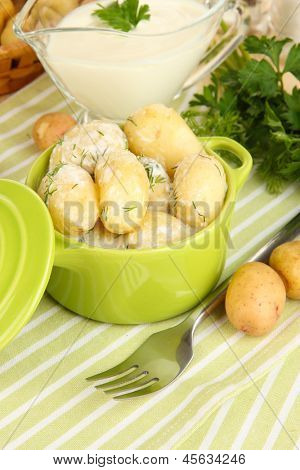 Gara giovane patate con panna acida e le erbe in padella sul primo piano tavolo in legno