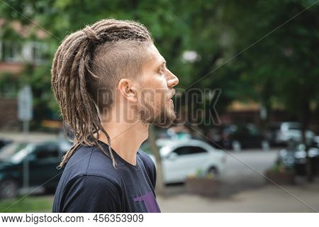 Profile Portrait Of A Caucasian Man With Dreadlocks, Beard And Sidecut On A Summer Outdoor