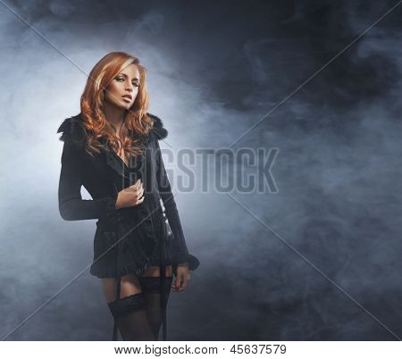 Beautiful and sexy striptease dancer over the smoky background
