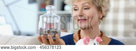 Portrait Senior Woman Hold Glass Container With Saved Money For Retirement. Put Coin In Piggybank Ev