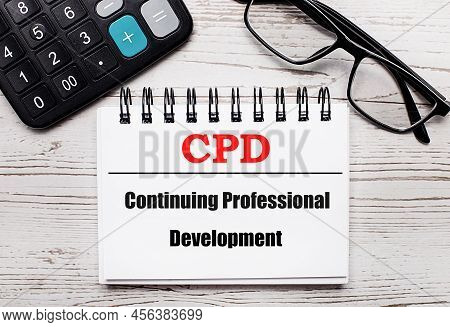 On A Light Wooden Table Calculator, Glasses And A Blank Notepad With The Text Cpd Continuing Profess