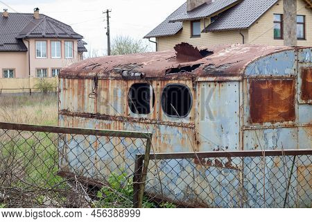 A Dilapidated Rotten And Rusty Metal Hut On A Work Site. An Old Tin Construction Trailer With A Roun