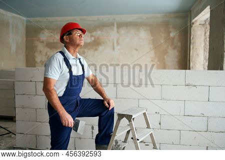 Professional Construction Worker In Uniform Standing With Spatula On Step Ladder. Portrait Of Contra