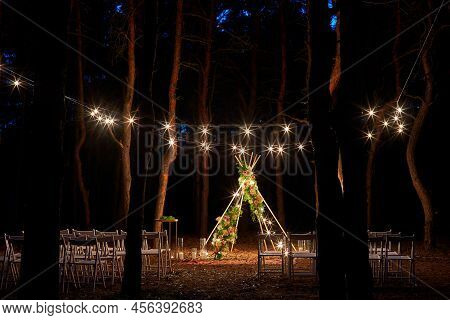 Festive String Lights Illumination On Boho Tipi Arch Decor On Outdoor Wedding Ceremony Venue In Pine