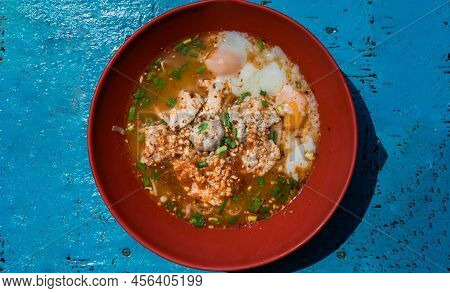 Spicy Tom Yum Egg Noodles Soup With Shrimp Dumplings And Medium-boiled Eggs, Pork Slices And Pork Me