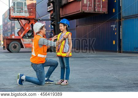 Father And Little Daughter Wearing A Safety Helmet At Container Cargo Site. Business Heir Concept. H