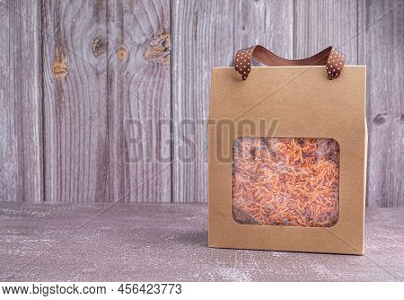 Package For Sale Of Sweet And Sour Crispy Noodles Or Mee Krob In The Thai Language Placed On A Gray 