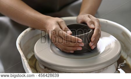 Unrecognized Ceramicist Creating Handicraft Crockery On The Pottery Wheel In Art Workshop. Pottery W