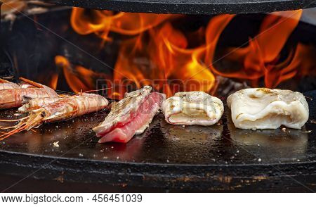 Close Up Seafood Cuisine. Grilled Fish, Squid, Shrimp Food Hot Bbq Charcoal Grill. Flames Fire Grill