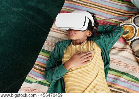 High Angle View Of African Little Boy Relaxing On Sofa And Using Vr Goggles To Watch Virtual Reality