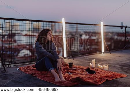 Unhappy Young Woman Resting And Sitting On The Roof With City View.