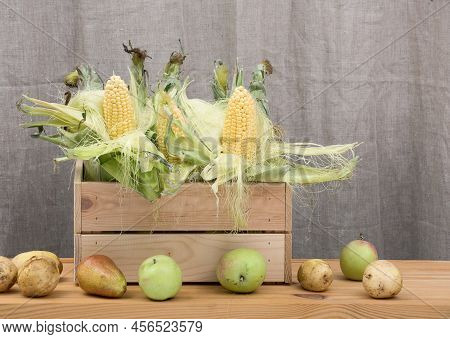 A Wooden Cruft Texture Box Full Of Fresh Young Corn With Green Lives And Juicy Autumn Pears And Gree