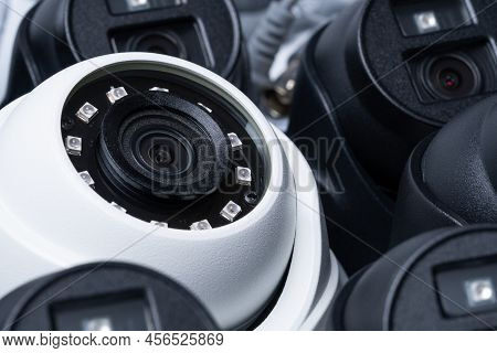 Close-up White Security Camera With Black Cameras Nearby.