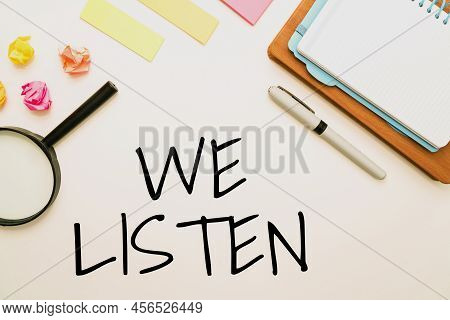 Sign Displaying We Listen. Business Concept Group Of Showing That Is Willing To Hear Anything You Wa