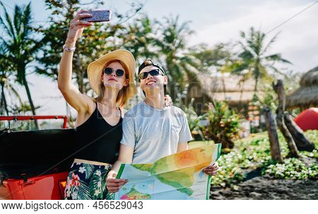Smiling Couple In Casual Clothes With Map And Smartphone Taking Selfie While Travelling And Spending