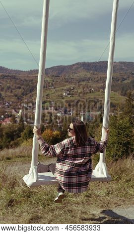 Young Brunette Woman Swinging On Mountain View On Carpathian Mountains In Ukraine