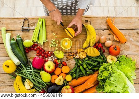 Top View Of Woman Chef Cutting And Preparing Healthy Natural Food On A Wooden Table - Vegatbles And 