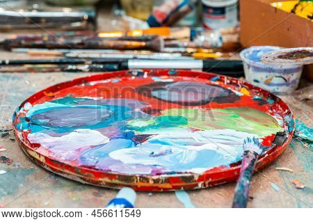 Bright Spots Of Paint In An Art Workshop With Brushes