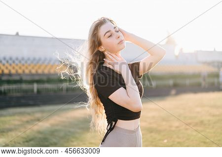 Pretty Young Girl Holds Her Hand Near Her Neck, Her Hair Flutters In Wind. Hot Sports Training. Girl
