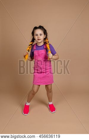 Serious Small Female Child With Hands On Two Kanekalon Pigtails Moving Looking At Camera With Missin