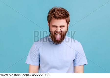 Portrait Of Young Adult Foolish Crazy Bearded Man Looking At Camera With Tongue Out Mouth, Having Ch
