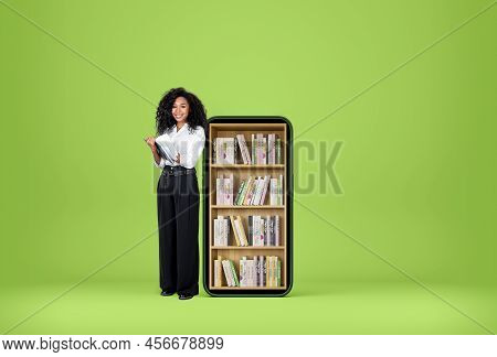African Businesswoman Smiling Near Smartphone And Take Note In Journal. Digital Library, Books In Ro