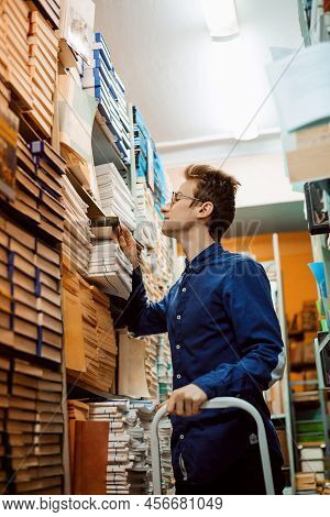 Student Standing On The Ledder Taking A Book From Shelf In Library