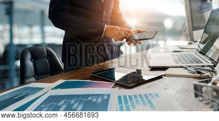 Businessman Using Mobile Smartphone And Laptop Analyzing Sales Data And Economic Growth Graph Chart.