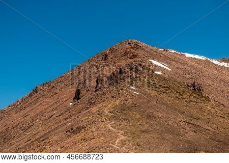 Brown High Mountain With A Trail For Tourists And Blue Sky