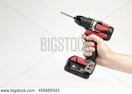 Cordless Drill In Black And Red. Screwdriver With A Drill In Hand On A White Background. Modern Carp