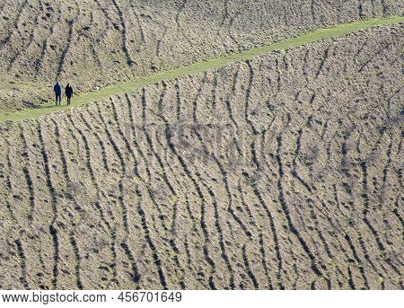 Two Distant Figures, Walking Through Unusually Shaped Hills In The English Countryside, Wiltshire, U