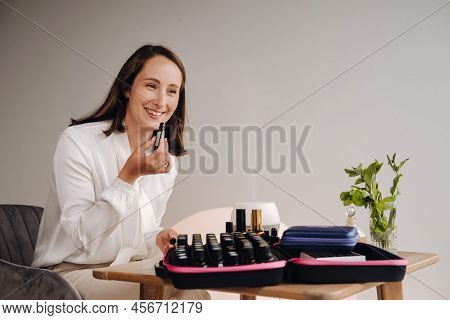 The Aromatherapist Girl Is Sitting In Her Office And Holding A Bottle Of Aromatic Oils. There Are Es